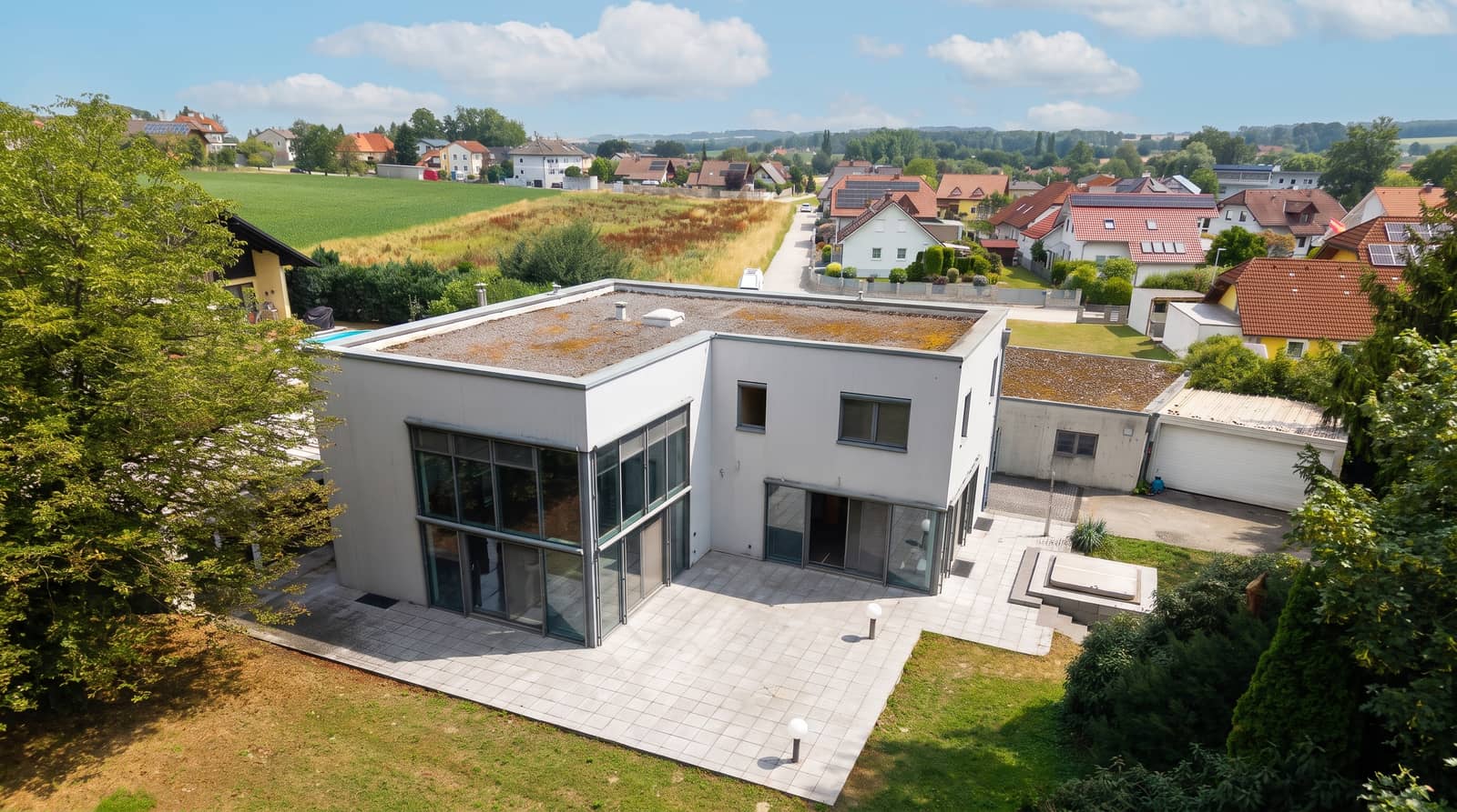 Luftaufnahme der kubischen Gartenfassade mit Terrasse und verglaster Gebäudeecke