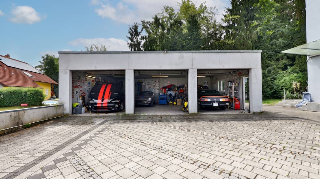 Dreifachgarage mit drei offenen Toren und gepflastertem Vorplatz